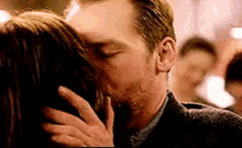 a man and woman are kissing in front of a crowd .