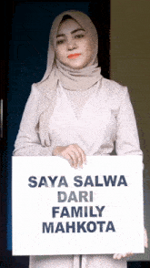 a woman in a hijab holds up a sign that says saya salwa dari family mahkota