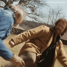 a man in a brown jacket is fighting another man in blue jeans