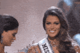 a woman is wearing a miss sash and smiling