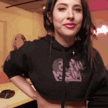 a woman wearing a black crop top that says ' i am sim ' on it
