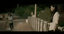 a blurry picture of a man and a woman standing next to a fence .
