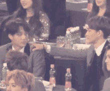 a group of people are sitting at a table with bottles of water on it
