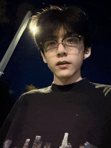a young man wearing glasses and a black shirt with a picture of the city on it