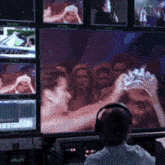 a man wearing headphones watches a woman holding a crown on a screen