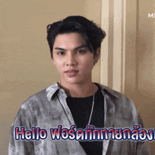 a young man is standing in front of a wall and says hello in a foreign language