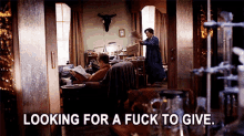a man reading a book in a living room with the words " looking for a fuck to give " above him