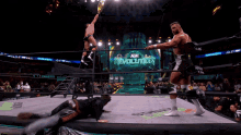 two wrestlers are in a ring with a sign that says revolution on it