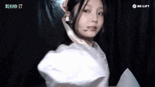 a woman in a white dress is wrapped in a white cloth and looking at the camera .