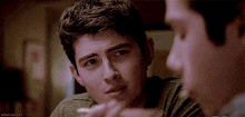 two young men are sitting next to each other and talking .
