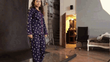 a woman in a polka dot pajama set stands in a room