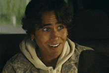 a man wearing a hoodie and earrings is smiling