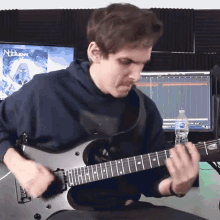 a man is playing a guitar in front of a computer screen that says nocturnal