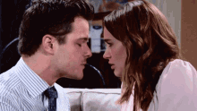 a man in a striped shirt and tie kisses a woman
