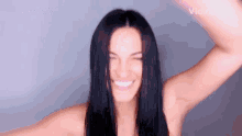 a woman with long black hair is smiling and making a funny face with her hands in the air .