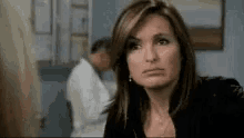 a woman is making a funny face in a room while a man is standing in the background .