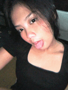 a woman sticking her tongue out in a black shirt