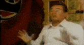 a man in a white shirt is standing in front of a red flag with a peace sign on it