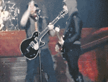 a pixelated image of two men playing guitars and singing into microphones