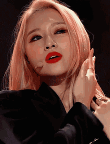 a woman with blonde hair and red lipstick holds her hand to her face