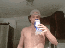 a shirtless man is drinking milk from a carton in a kitchen