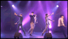 a group of men dancing on a stage with purple lights