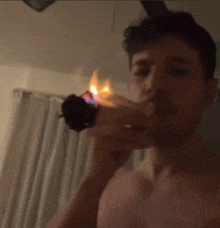 a shirtless man is lighting a cigarette with a lighter .