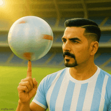 a man in a blue and white striped shirt holds a ball on his finger