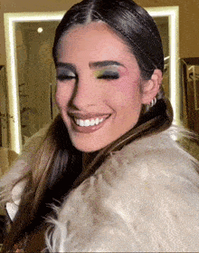 a woman wearing a white fur coat is smiling