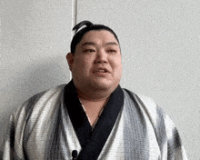 a man with a ponytail on his head is wearing a kimono