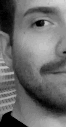 a close up of a man 's face with a beard in a black and white photo