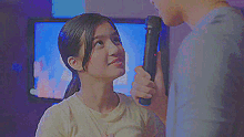 a man is talking into a microphone while a woman looks on .