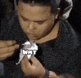 a man is eating a piece of paper with the word wmt on it .