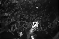 a man singing into a microphone in front of a crowd with a sign that says ' a.m. '