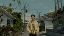 a man in a yellow jacket is walking down a street in a residential area