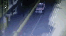 a car is driving down a street at night with a building in the background .