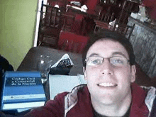 a man wearing glasses is taking a selfie in front of a book titled código civil y comercial de la nacion .