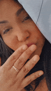 a woman covering her mouth with her hand with a ring on her finger