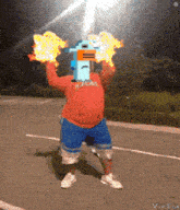 a man in a red shirt and blue shorts is holding flames in front of his head
