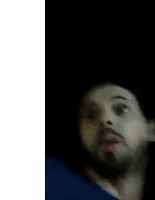 a man with a beard and a blue shirt is making a funny face .