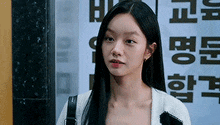 a woman with long black hair is standing in front of a building with a sign in korean .