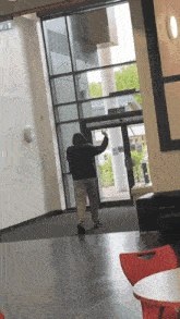 a man in a black hoodie is standing in front of a large glass door