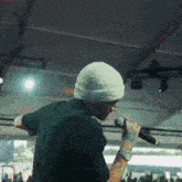 a man is singing into a microphone while wearing a white beanie