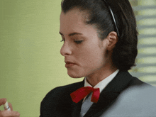 a woman wearing a suit and red bow tie