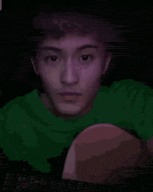 a man in a green shirt is making a funny face with his hands .
