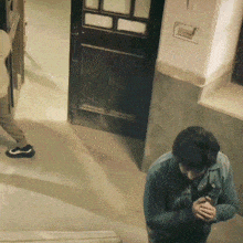 a man is standing in front of a door in a hallway .
