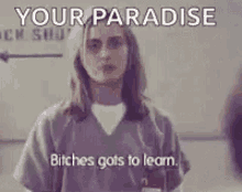 a woman in a jail uniform is standing in front of a sign that says `` your paradise bitches got to learn '' .