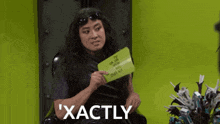 a woman is holding a piece of paper that says ' exactly ' on it