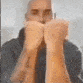 a man is covering his face with his hands in a blurry picture .