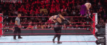 two wrestlers are in a wrestling ring with a referee watching .